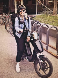 Émilie Martz-Kuhn sur sa motocyclette, casque sur la tête et lunettes fumées, relax et souriante.